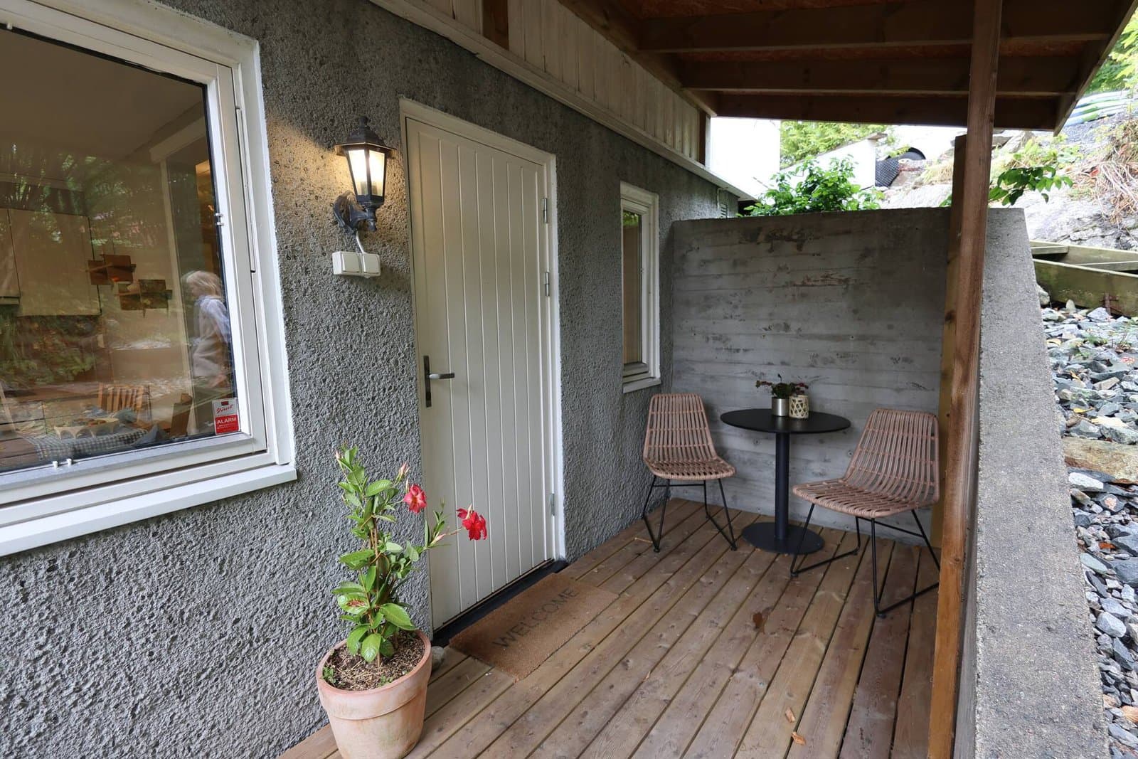 Inngangen til Lille Solbakken — overbygd uteplass med to stoler og et lite bord, klar til ankomst